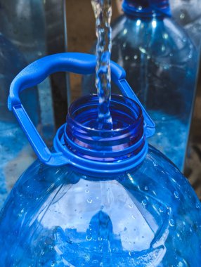 close-up of fresh clean water being poured into a large blue plastic bottle