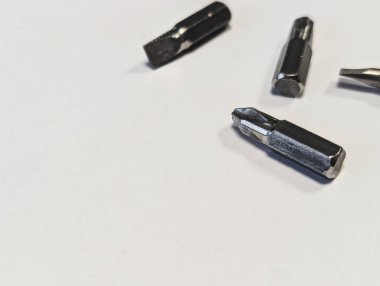three metal screwdriver bits on white background with large copy space