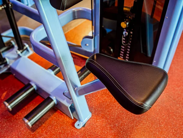 Modern jimnastik makinesinin yakın çekimi ve dokulu kırmızı zeminde açık mavi çerçeve.