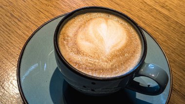 Seramik kapuçino bardağının en üst görüntüsü. Güzel kalp şekilli latte sanatı.