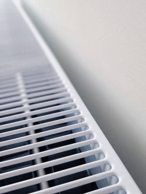 Beyaz panelli ısıtma radyatörünün dikey yakın plan görüntüsü kopyalama alanı olan minimalist beyaz bir duvara karşı.