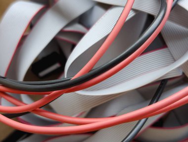 Sarmal gri kurdele veri kablosu ve kırmızı ve siyah elektrik kablolarının birbirine karışmış soyut arkaplanı, yakın plan.