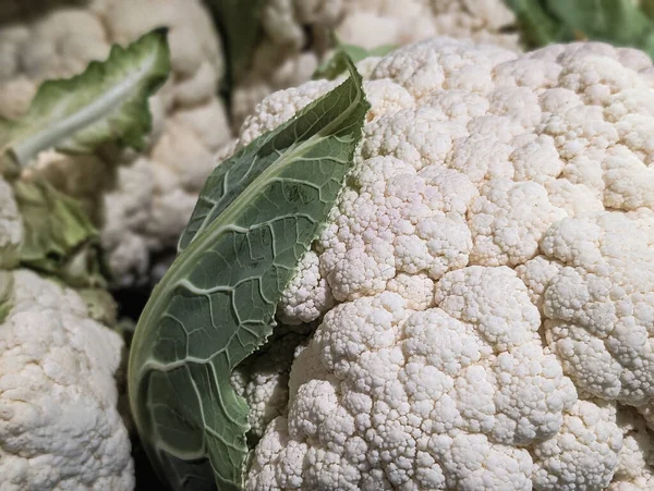 Taze çiğ karnabahar başını ve yeşil yaprak makro dokusunu kapat