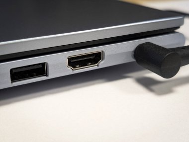 Metalik dizüstü bilgisayarın HDMI ve USB portlarını bağlı bir kablo ile gösteren tarafını kapat