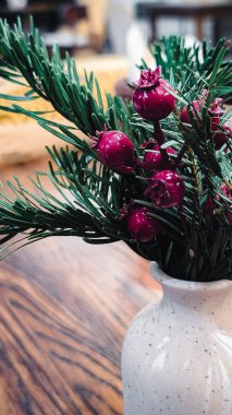 Kırmızı böğürtlenli ve vazoda yeşil dallı Noel süslemeleri.