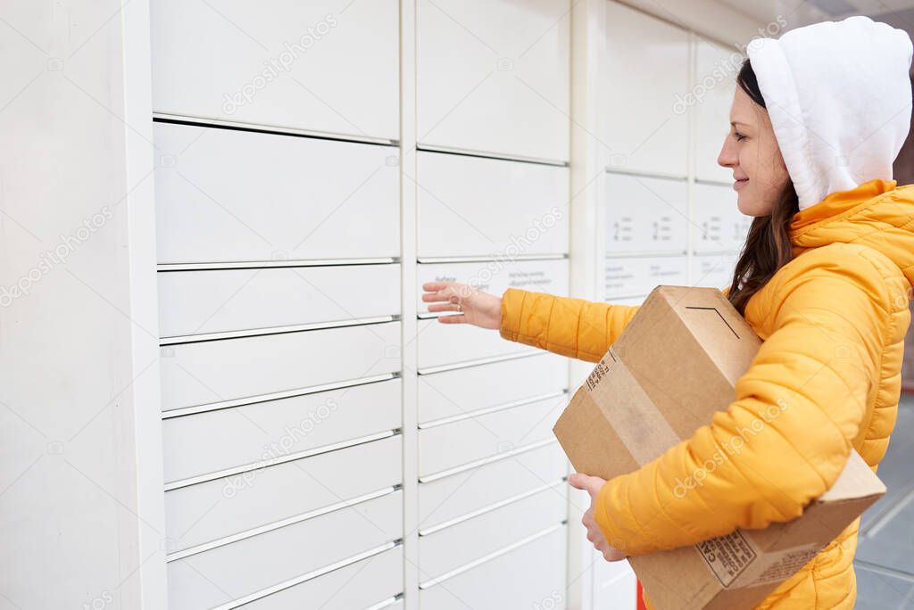 the girl is trying to open the parcel locker to send the parcel. Receiving package.