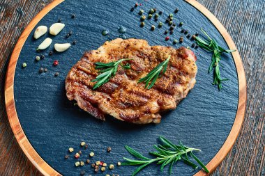 Domuz yağıyla pişirilmiş domuz bifteği, ahşap bir tahtanın üzerinde sarımsak, biberiye, tuz ve biber ile birlikte yatıyor. Et çok lezzetli. Bir sürü yağ. en üstteki görünüm.