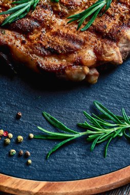 Biberiye ve biberiye, ahşap bir tahtanın üzerinde domuz yağıyla pişirilmiş domuz bifteğinin yanında yatar. Et çok lezzetli..