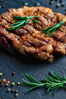 Biberiye ve biberiye, ahşap bir tahtanın üzerinde domuz yağıyla pişirilmiş domuz bifteğinin yanında yatar. Et çok lezzetli. dikey çekim.