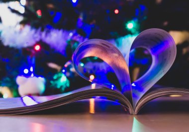 Arka planda Noel ağacı olan kağıt kitaptan kalp şekli