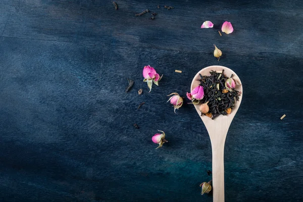 Tea leaves with rose buds in wooden  background. — Stock Photo, Image