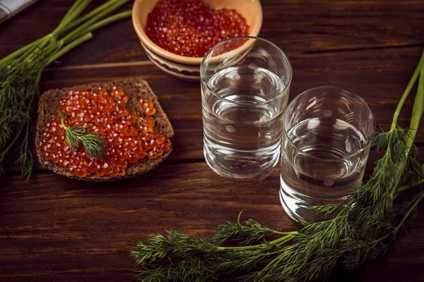 Caviar de salmón rojo y vodka ruso sobre mesa de madera —  Fotos de Stock