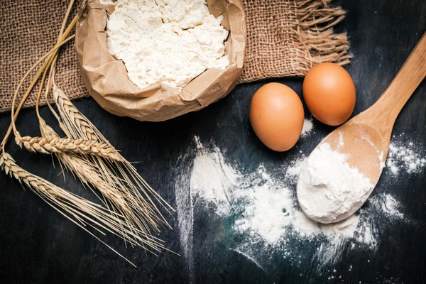 Wheat ears and flour on rustic background