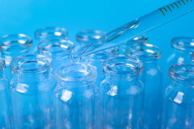 Mavi arkaplandaki cam şişeye reaktör bırakılıyor. Yakın plan. Çiftlik ve tıbbi konsept geçmişi