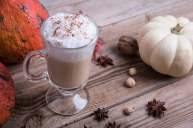 Ahşap masada kremalı latte, sonbahar arkaplanı.