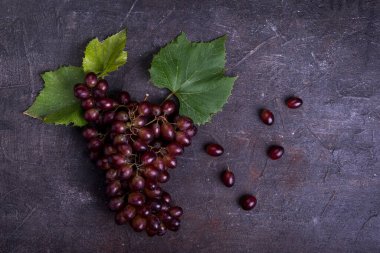 Koyu arkaplanda yaprakları olan bir demet üzüm..