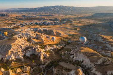 Sıcak hava balonları güneş doğarken kayaların üzerinde uçuyor, Kapadokya, Türkiye