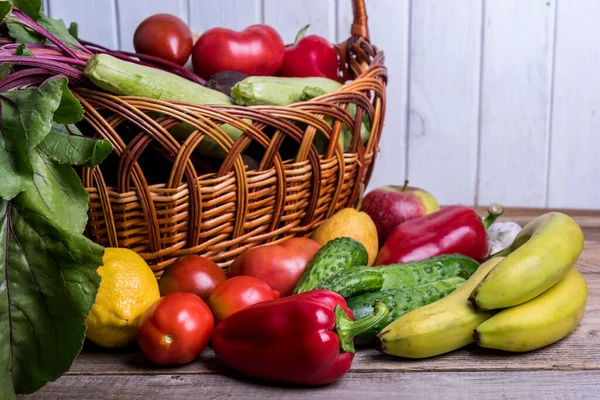 Fresh vegetables and fruits in basket on rustic wooden table