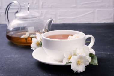 Yeşil çay ile yasemin beyaz fincanda gri arka planda