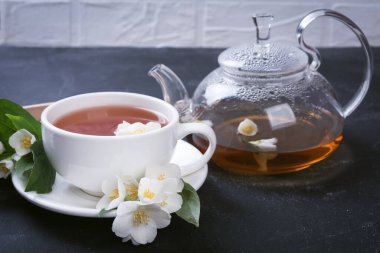 Yeşil çay ile yasemin beyaz fincanda gri arka planda