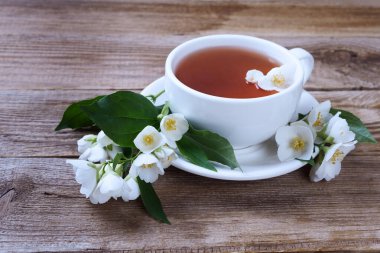 Yeşil çay, yasemin ve beyaz bardakla ahşap kırsal masada. 