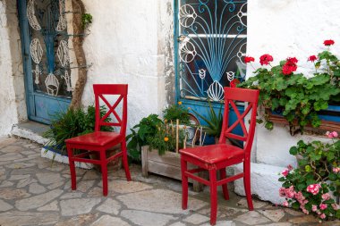 Yunanistan 'ın Korfu kentindeki Afionas köyünde beyaz Yunan evleri ve kırmızı sandalyeli otantik cadde