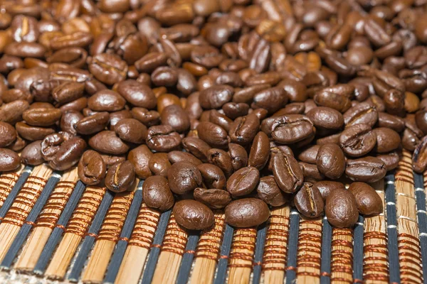 Selezione di chicchi di caffè tostati su un tappetino di bambù . — Foto Stock
