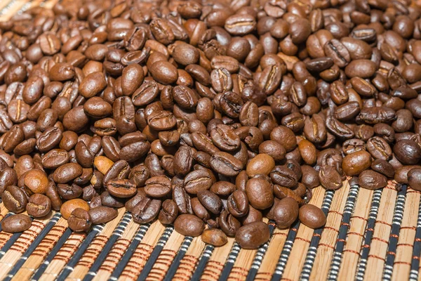 Chicchi di caffè tostati su un tappetino di bambù — Foto Stock