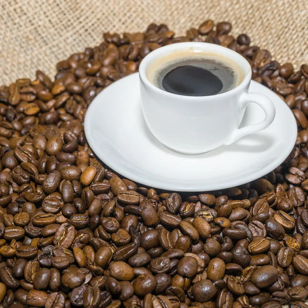 Chicchi di caffè su iuta e tazza di caffè . — Foto Stock