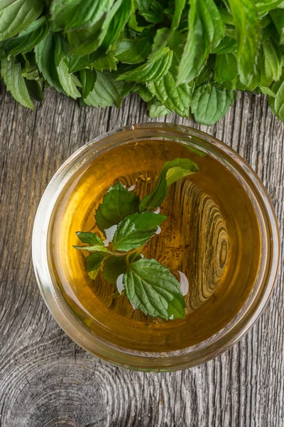 Tè alla menta con foglie di menta fresca su sfondo di legno — Foto Stock