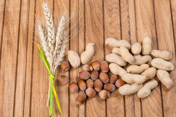 Ořechy s ušima pšenice na dřevěný stůl. — Stock fotografie