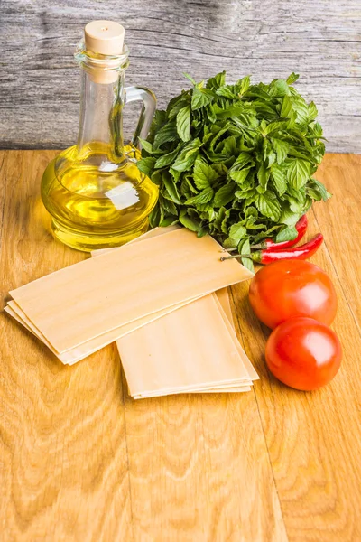 Voorbereiding van Italiaanse lasagne met verse rode tomaten en mint op vellen gedroogde pasta — Stockfoto