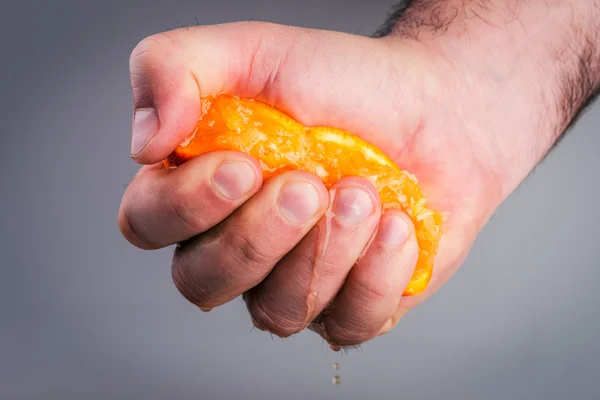 Mano masculina apretando naranja sobre fondo de morera . — Foto de Stock