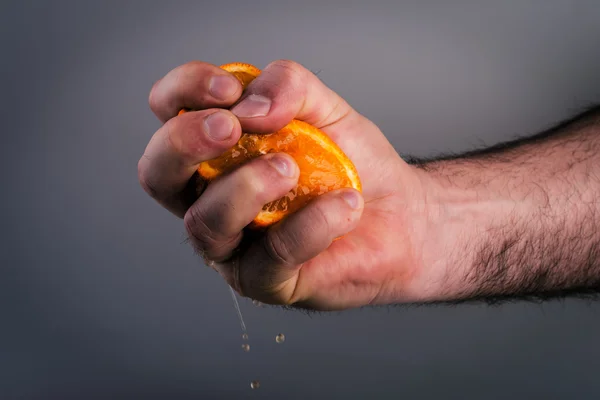 Mano masculina apretando naranja sobre fondo de morera . —  Fotos de Stock