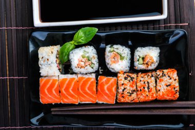 suşi rulo ürün yelpazesine Soya soslu beyaz plaka ve yemek çubukları.