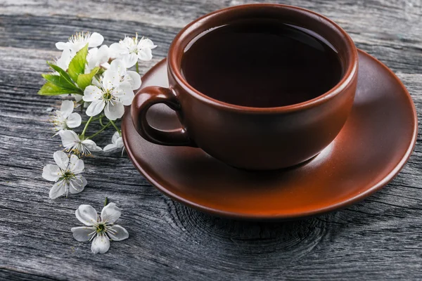 Xícara de chá e cereja ramo em um fundo de madeira . — Fotografia de Stock