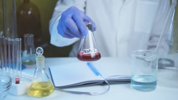 Chemical laboratory food supply. GMO Genetically modified products in the laboratory. A lab technician in a white coat holds nitric acid in his hand. — Stock Video