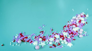 Mavi arkaplanda izole edilmiş renkli şeker parçacıkları.