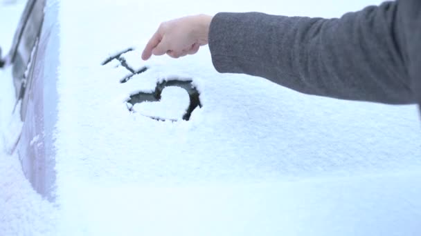 Ich liebe es, im Schnee auf der schneebedeckten Windschutzscheibe des Autos geschrieben — Stockvideo