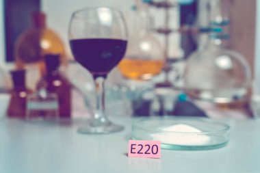 Fotoğraf Şarap Laboratuvarı. Sülfür dioksit içeriği için şarap testi. Petri kabında e-katkı maddeleri ve sülfür dioksit kristalleri olan renkli bir plaka..