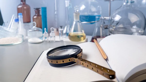 Photo The magnifying glass is on the notebook of the table in the laboratory.