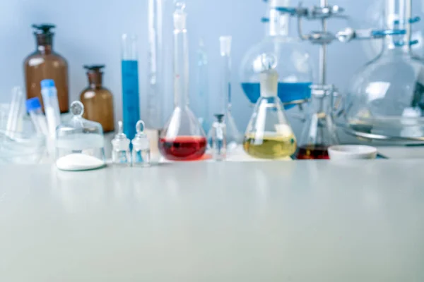 Kolven, reageerbuizen en laboratoriumglaswerk met oplossingen van verschillende kleuren op de tafel in het laboratorium. Stockfoto