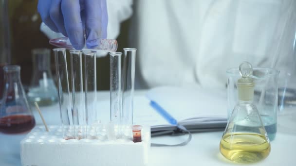 Scientist tests blood and adds test tube in rack at lab. Concept of health and safety life. — Stock Video