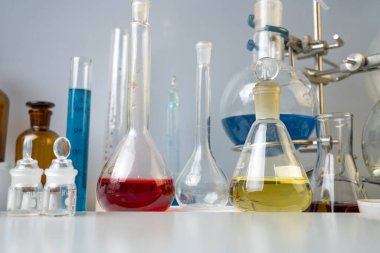 Şişeler, test tüpleri ve laboratuvar bardakları. Laboratuvardaki masada farklı renklerin çözümleri var..