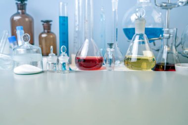 Şişeler, test tüpleri ve laboratuvar bardakları. Laboratuvardaki masada farklı renklerin çözümleri var..