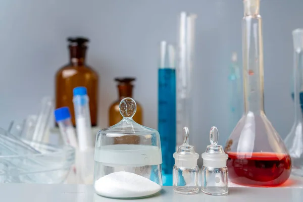 Frascos com pó químico, copos de laboratório com soluções sobre a mesa em laboratório. — Fotografia de Stock