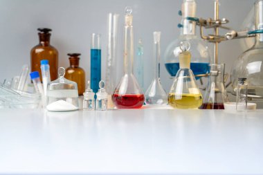 Fotoğraf şişeleri, test tüpleri ve laboratuvar bardakları. Laboratuvardaki masada farklı renklerin çözümleri var..