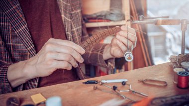 Balık tutmak için sinek bağlayan genç adamların ellerine yaklaş.