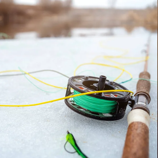 Winter fly fishing picture. Fly rod and reel on snowy river bank. — Stock Photo, Image