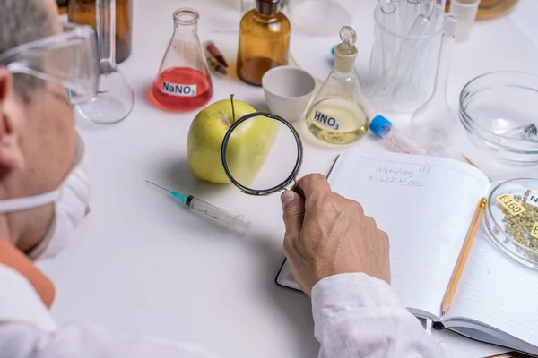 Food specialist looking at green apple through magnifying glass, food quality — Foto de Stock